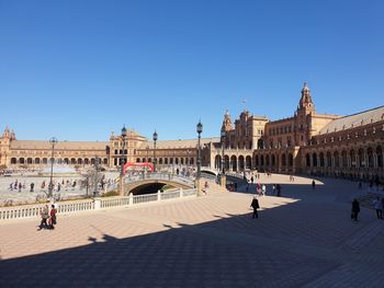 Group of people in front of building against clear blue sky