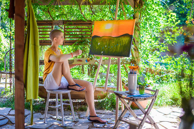 Young female artist working on her art canvas painting outdoors in her garden. art therapy.