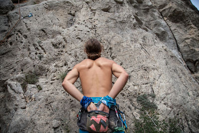 Rear view of shirtless man standing against rock formation