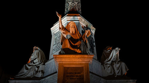Low angle view of statue against building against sky at night