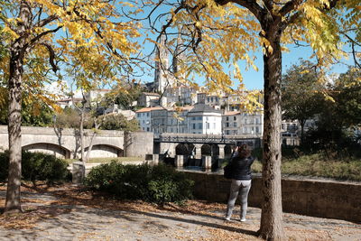 Rear view of woman standing by bridge in city