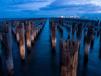 Panoramic view of wooden posts in sea against sky