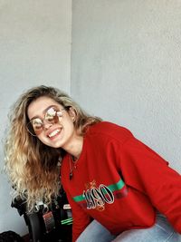 Portrait of a smiling young woman against wall