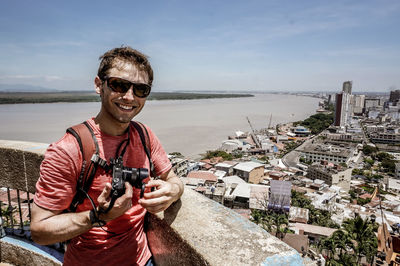 Portrait of smiling man standing at sea against sky
