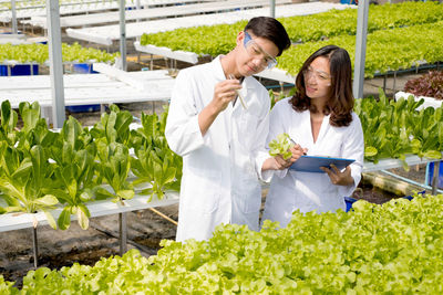 Young woman looking away while standing by plants