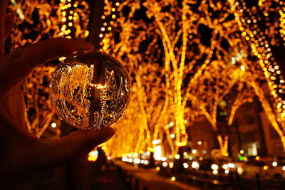 Close-up of hand holding illuminated glass