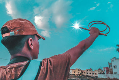 Low angle view of man holding umbrella against sky