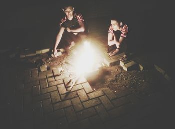 People sitting by bonfire at night