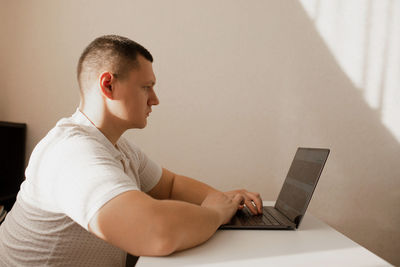 Side view of man using laptop at cafe