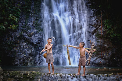 Full length of shirtless boy playing in forest