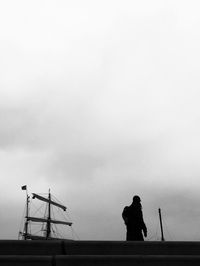 Rear view of silhouette man standing against at harbor