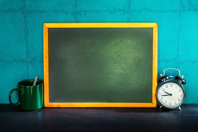 Close-up of clock on table against blue wall