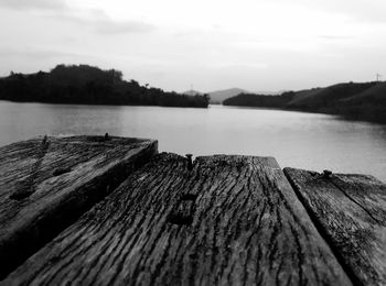 Close-up of wooden pier over lake against sky