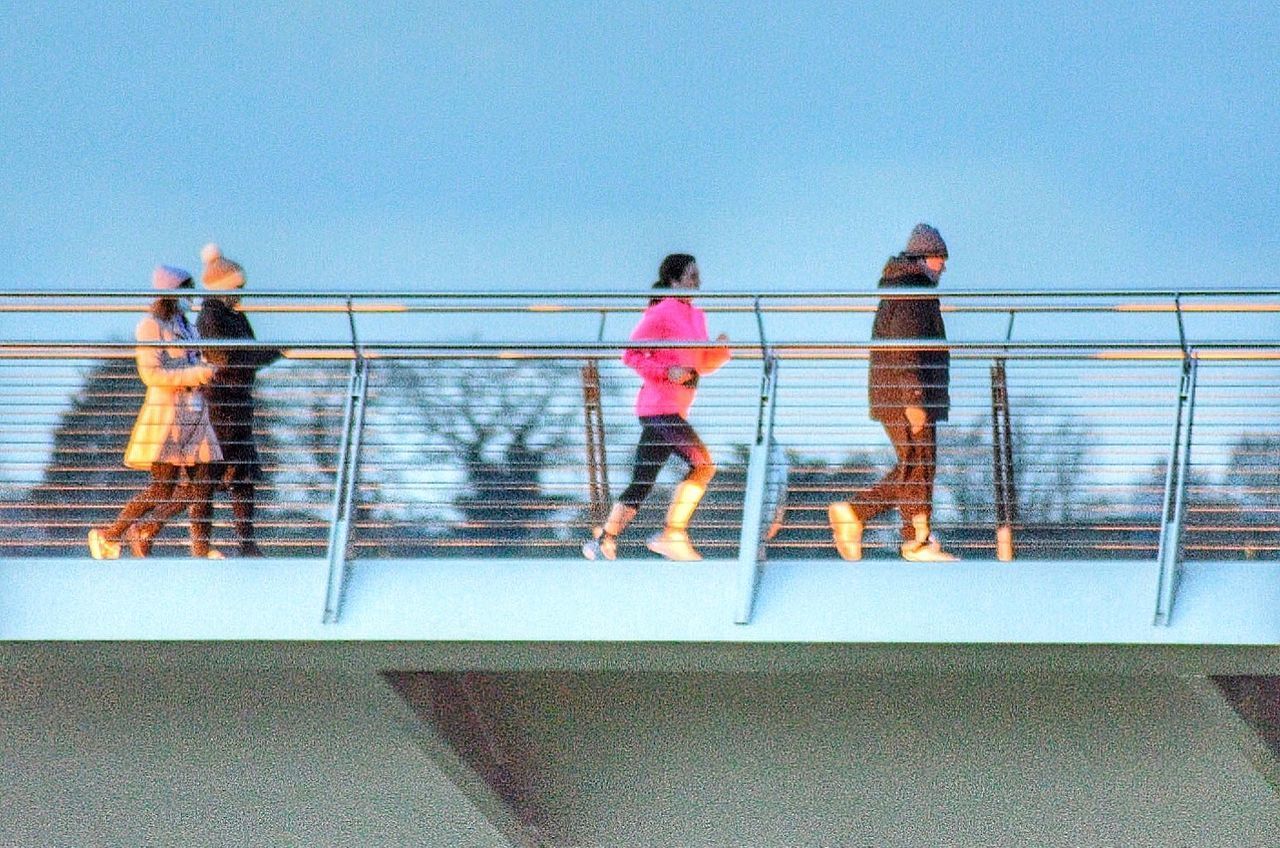 PEOPLE STANDING BY RAILING AGAINST SKY