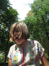 Girl looking away while standing against trees