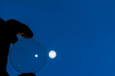 Close-up of hand against blue sky