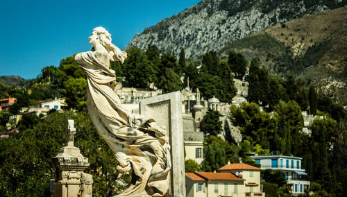 Statue in city against sky