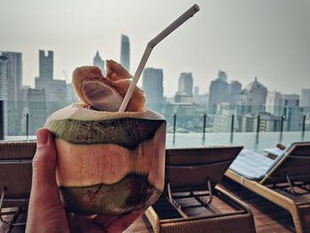 Close-up of person holding ice cream against buildings in city