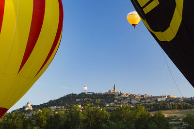Hot air balloons flying in city against clear blue sky