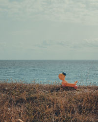 Man relaxing on chair at beach against sky