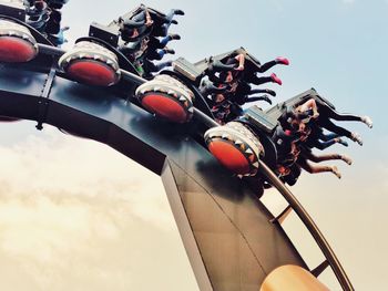 Low angle view of people in amusement park ride against sky