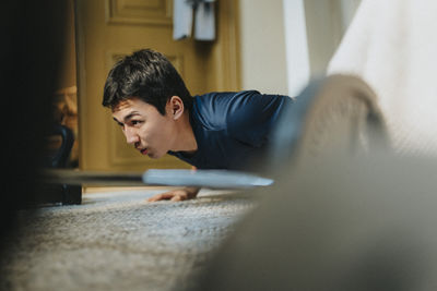 Dedicated teenage boy doing push-ups at home