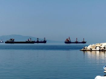 People sailing on sea against clear sky