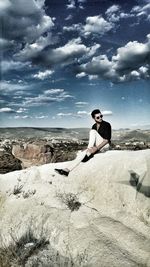 Full length of man sitting on rock formation at cappadocia against sky