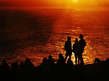 Silhouette people standing at beach during sunset