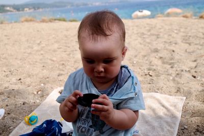 Boy holding mobile phone at beach