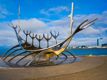 Metallic structure on beach against blue sky