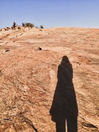 Shadow of man walking on landscape against sky