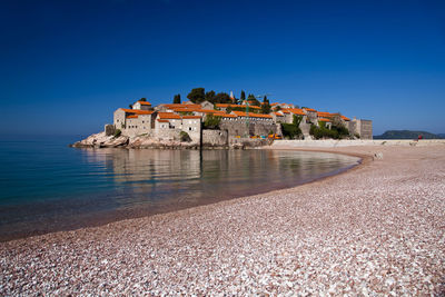 Castle on beach against clear blue sky