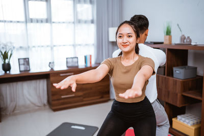 Young woman using mobile phone while sitting on table