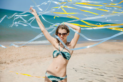 Young woman wearing sunglasses standing on beach