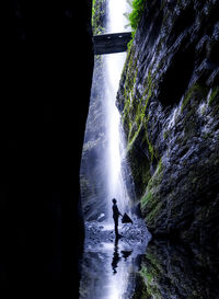Silhouette person on rock against waterfall