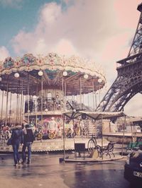 Rear view of people at amusement park against sky