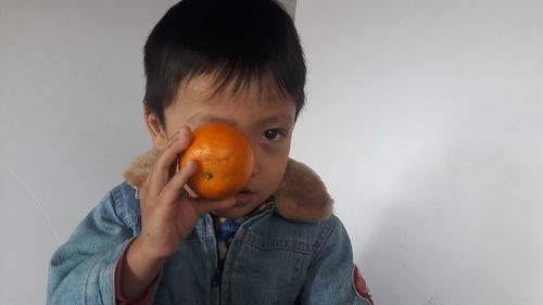 Portrait of boy holding apple against white background