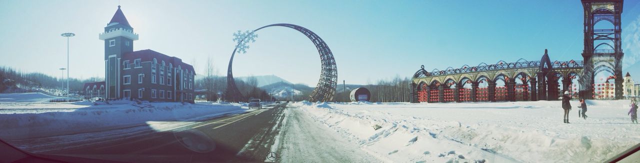 snow, winter, cold temperature, architecture, built structure, transportation, building exterior, season, clear sky, city, car, mode of transport, land vehicle, incidental people, street, road, street light, weather, travel, covering