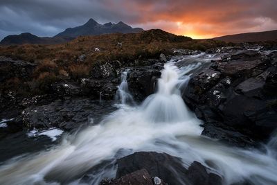 View of stream flowing through landscape at night