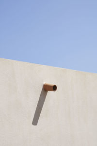 Low angle view of electric lamp on wall against clear sky