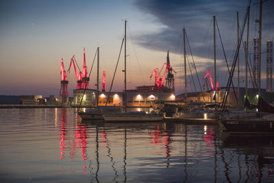 Boats moored at harbor against sky during sunset