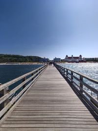 Footbridge over pier against clear sky