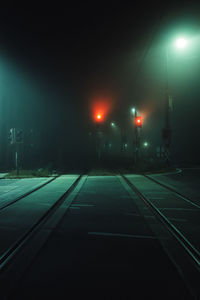 Illuminated railroad tracks against sky at night