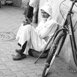 Portrait of smiling woman sitting on footpath