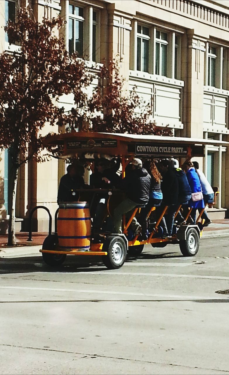 PEOPLE RIDING MOTORCYCLE ON STREET AGAINST BUILDINGS