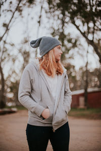 Woman looking away while standing on tree