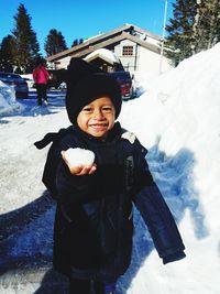 Portrait of cute boy holding snow while standing on land