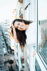 Side view of young woman standing against window