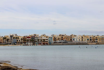 Buildings by sea against sky